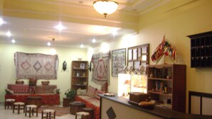 A living room with a sofa, chairs, a coffee table, and a TV. There are bookshelves and a chandelier. - Hotel Baykal (Bogazkale)