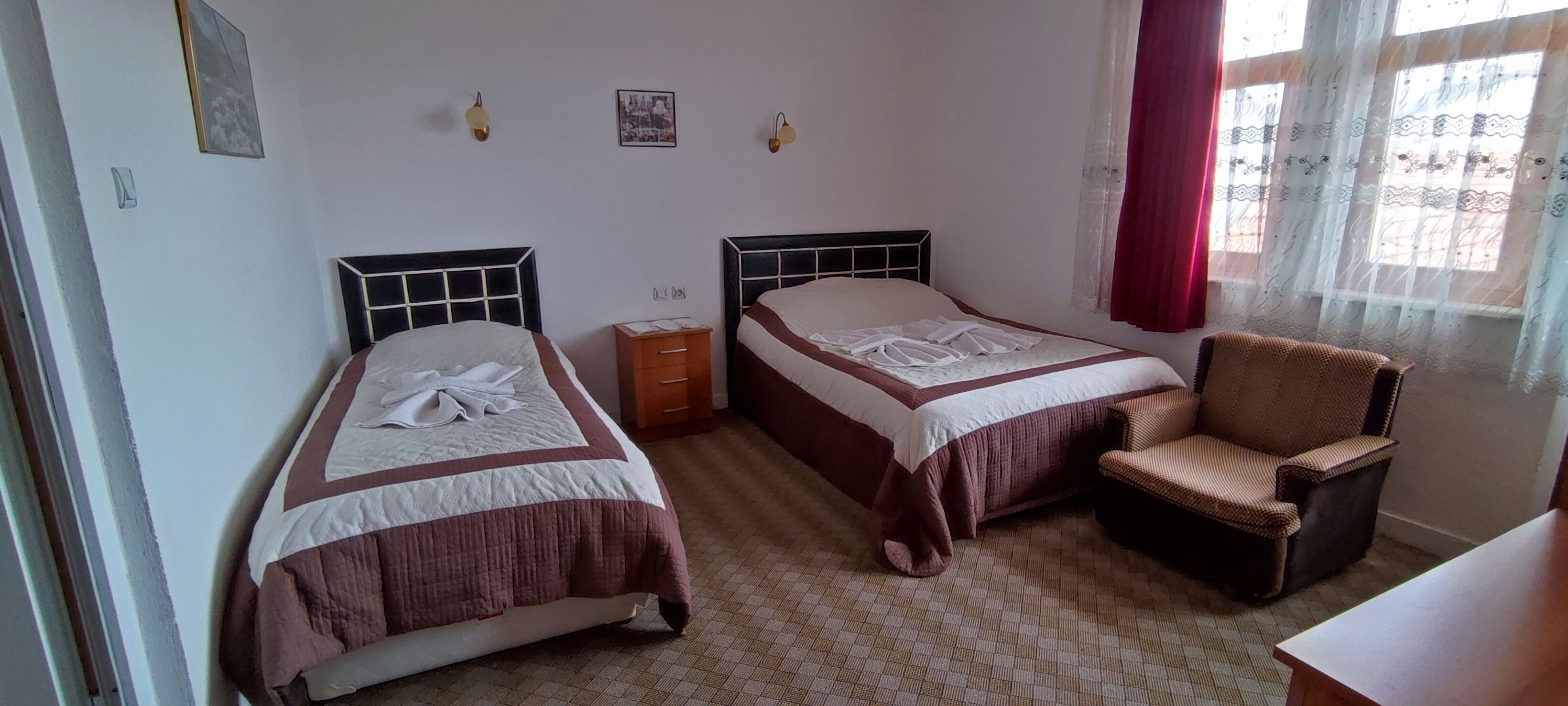 A bedroom with two beds, a chair, and a nightstand.