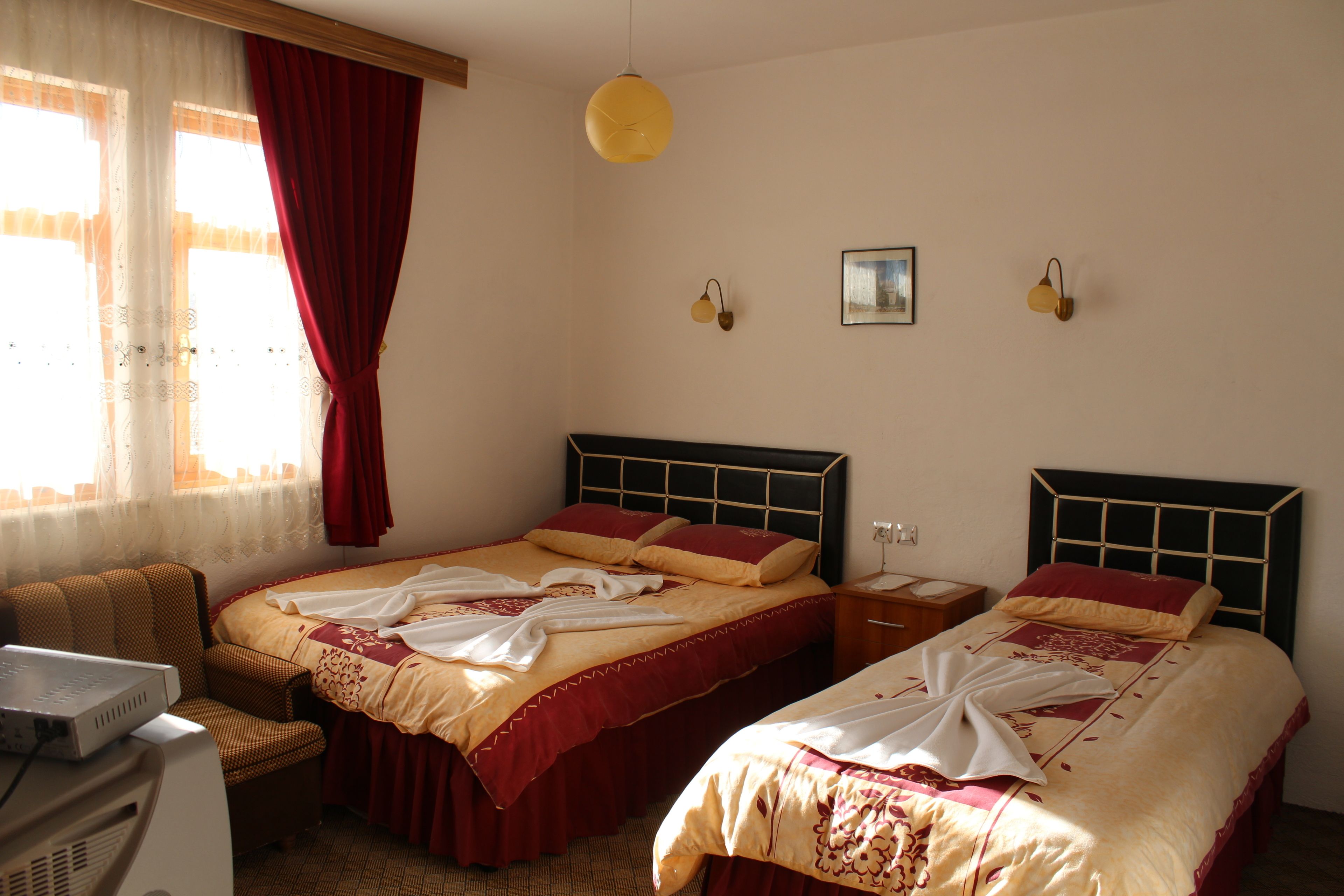 Habitació d'hotel amb dos llits, escriptori, cadira i finestra amb cortines.