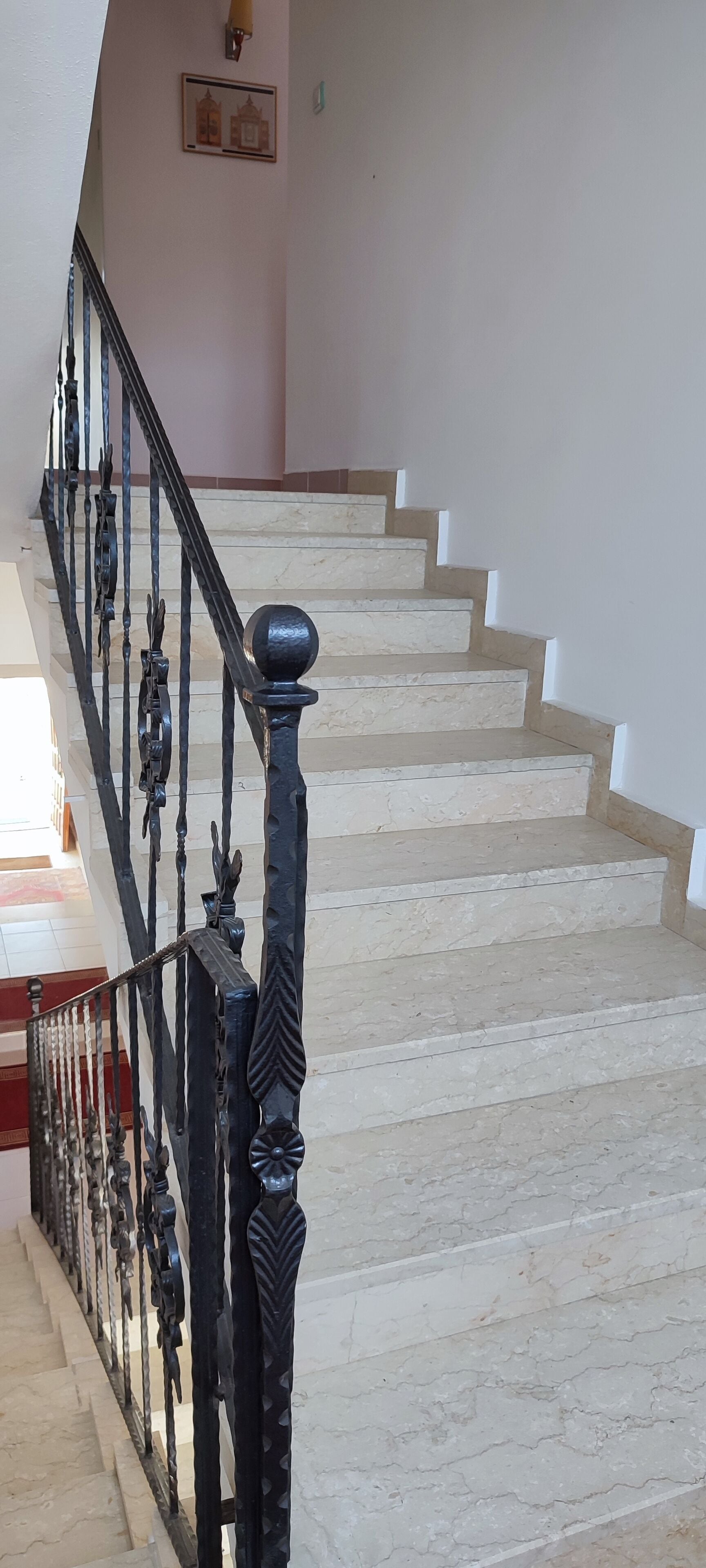 A staircase with a black metal railing and a marble finish.
