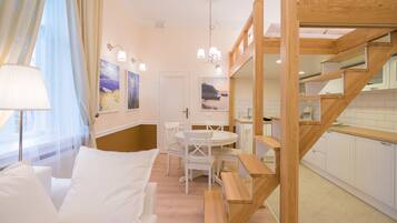 Ett modernt hotellrum med en trätrappa, en matplats med ett runt bord och utsikt över havet genom fönstret.