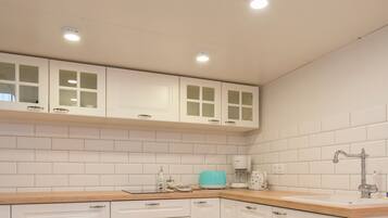 A kitchen with white cabinets, a wooden countertop, a sink, and a coffee maker.