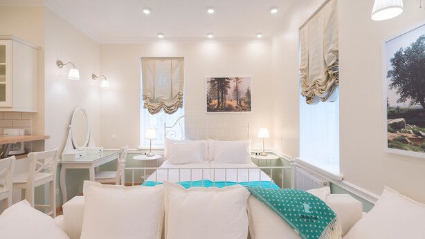 Un dormitorio con cama, mesitas de noche, un espejo y una ventana con cortinas.