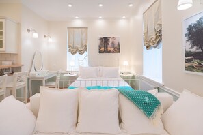 A bedroom with a bed, bedside tables, a mirror, and a window with curtains.