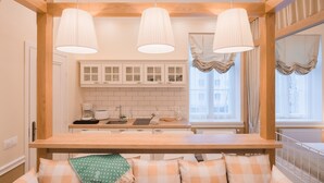 Una cocina moderna con vigas de madera, armarios blancos y luces colgantes.