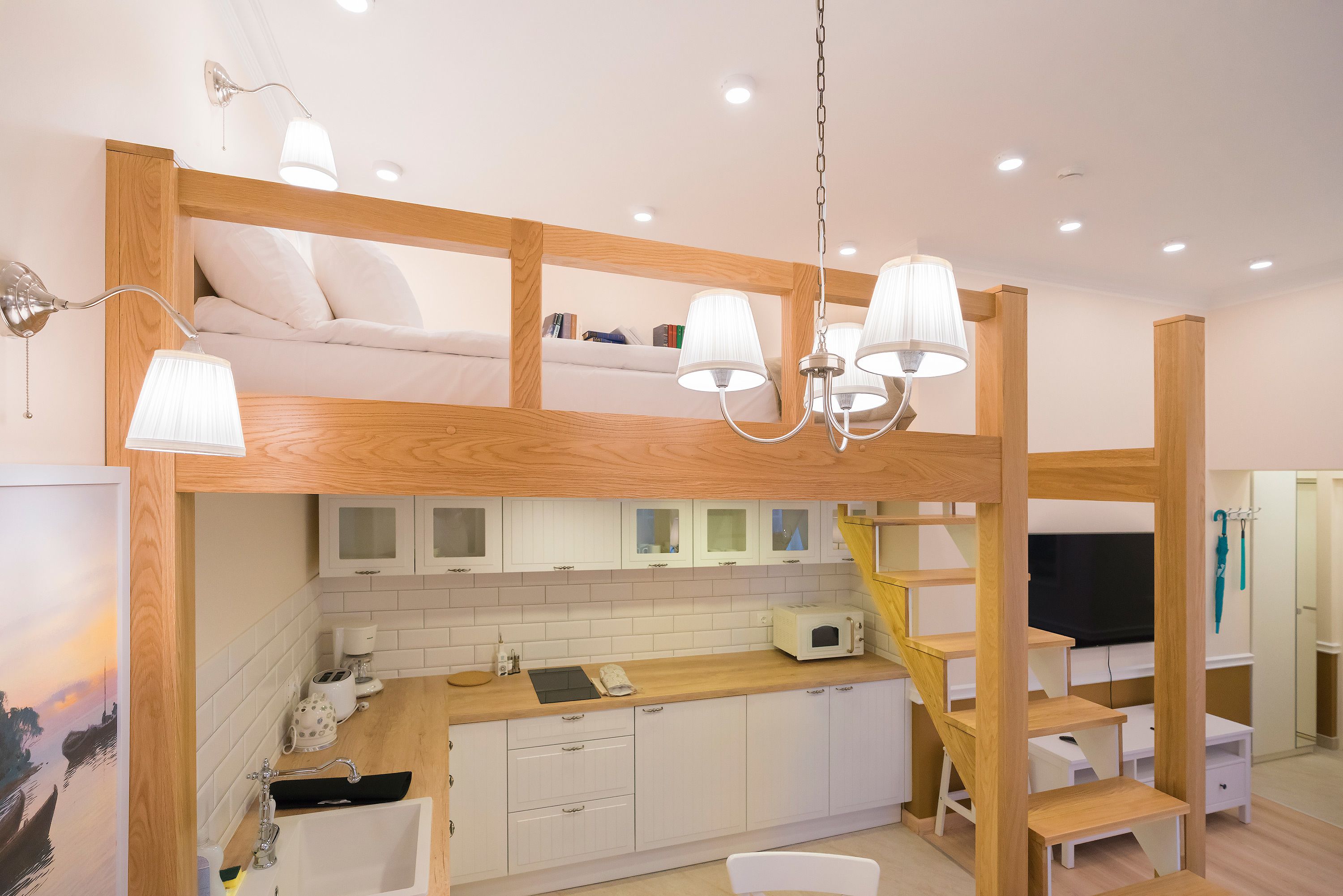 A compact, modern room with a bunk bed, kitchenette, and a TV.