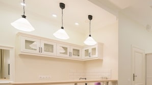 Una cocina moderna con armarios blancos, una zona de comedor con sillas blancas y un sofá blanco.