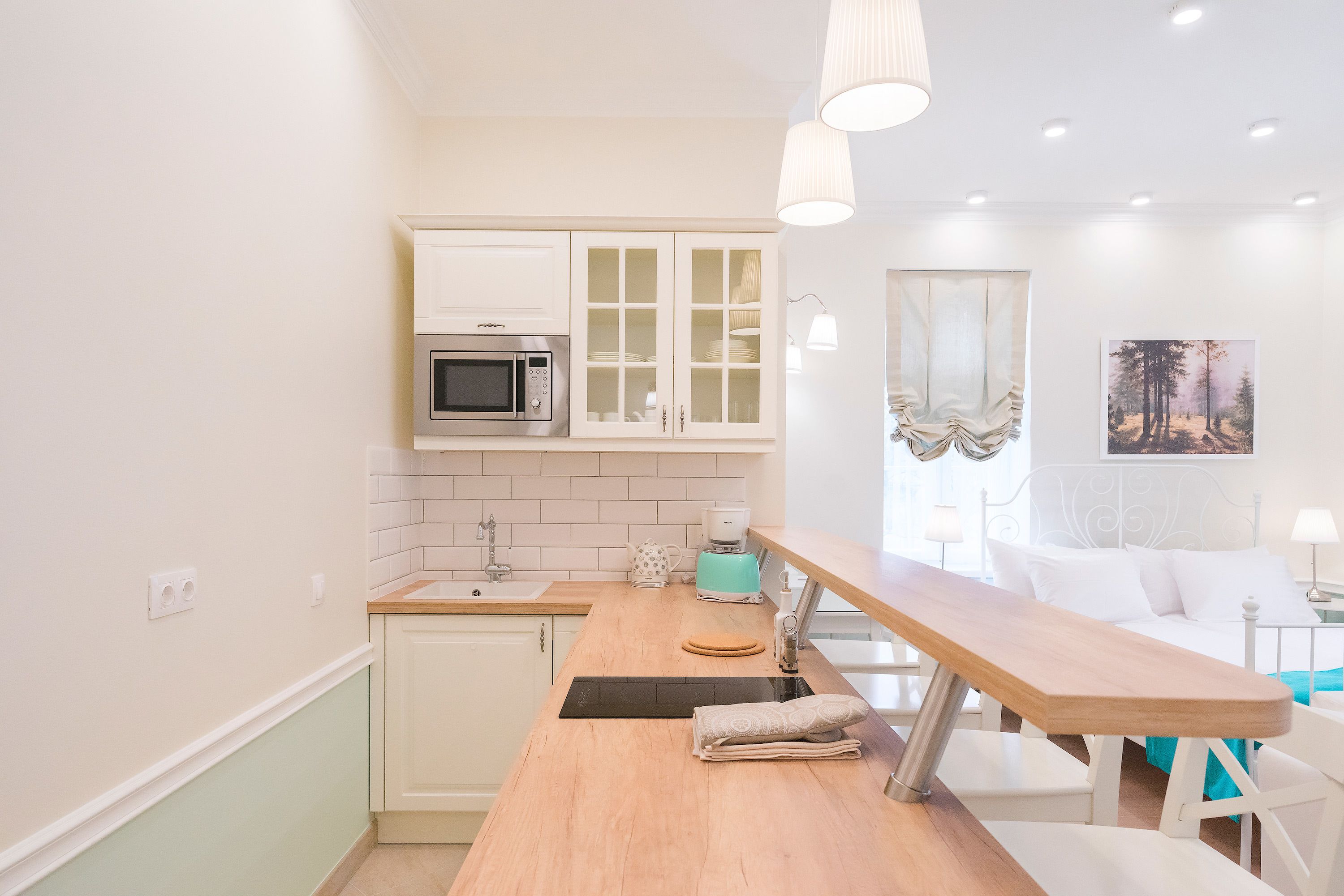 A compact kitchen with white cabinets, a microwave, and a coffee maker.