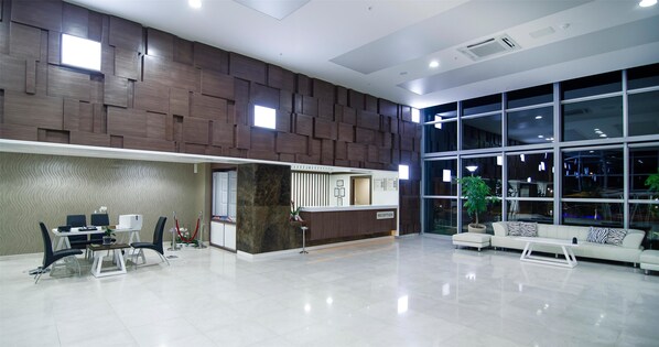 A modern reception area with a reception desk, seating, and a large window providing a view of the outside.