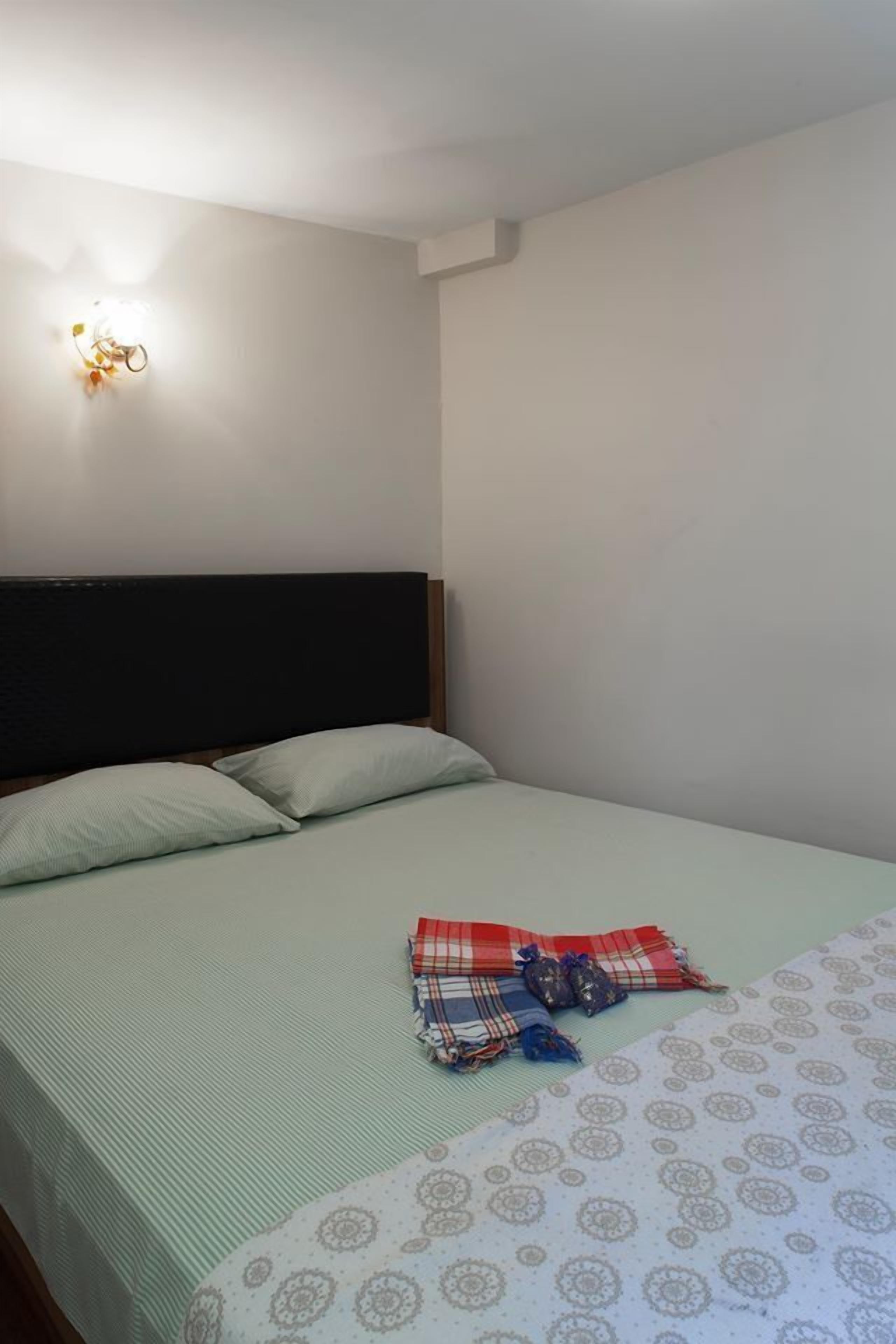 Una cama individual con cabecera, una lámpara de pared y una colcha estampada.