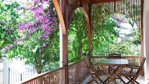 Un espacio al aire libre cubierto con una mesa y sillas de madera, rodeado por una valla y arcos de madera.