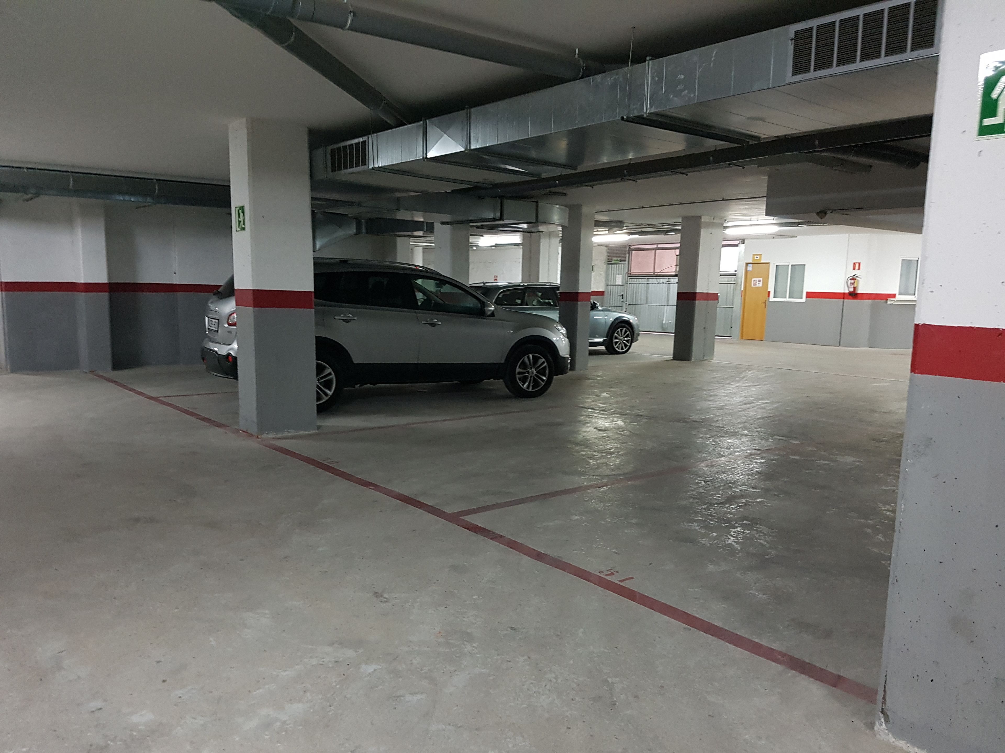 Een meerlaags parkeergarage met betonnen vloeren en zuilen, met een auto geparkeerd op een van de plaatsen.