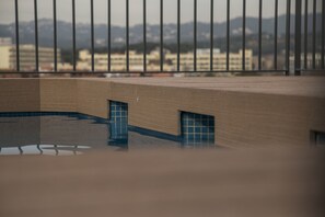 A view through a metal fence of a building with a pool and a door. - Apartaments Ponent (Lloret de Mar)