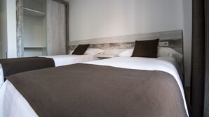 Habitació d'hotel amb dos llits, un panell de capçalera de fusta i un armari.