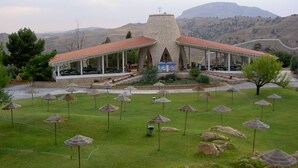 A building with a stone tower and a covered patio area. - Balneario de Alicún de las Torres (Villanueva de las Torres)