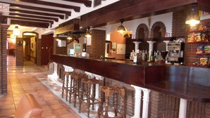 A bar area with a long counter, stools, and a tiled floor. - Balneario de Alicún de las Torres (Villanueva de las Torres)