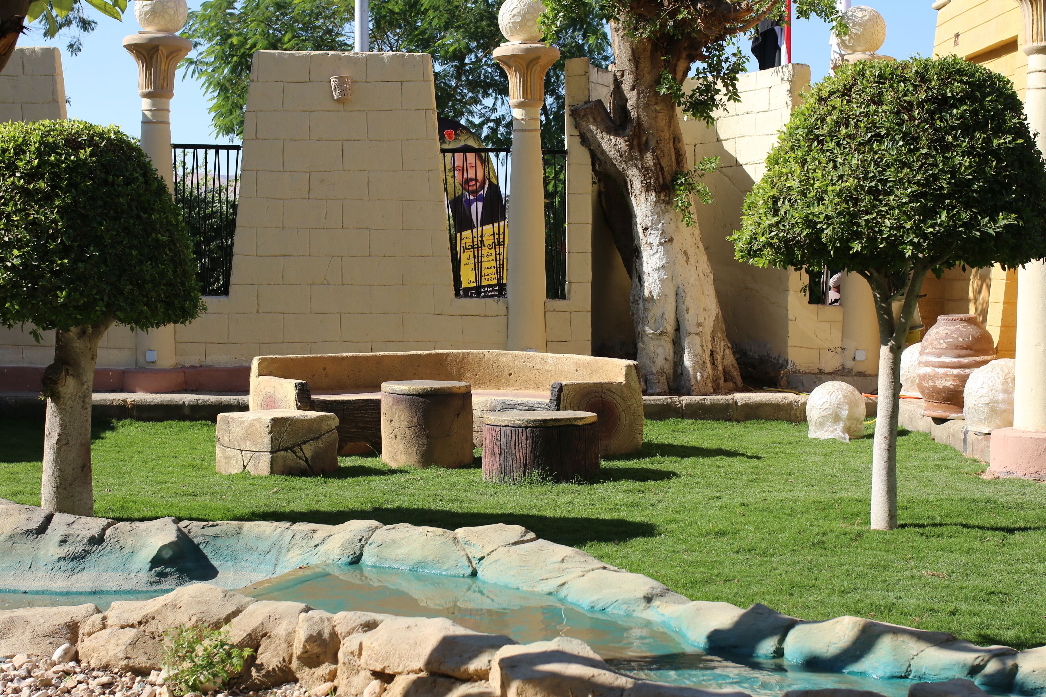A courtyard with a fountain, stone seating, and a mural on a wall.