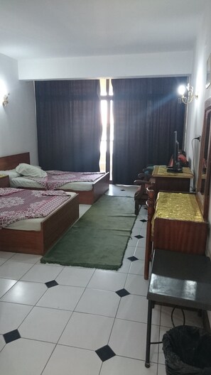 Habitación de hotel con dos camas, un escritorio, una silla, un televisor y una ventana con cortinas.