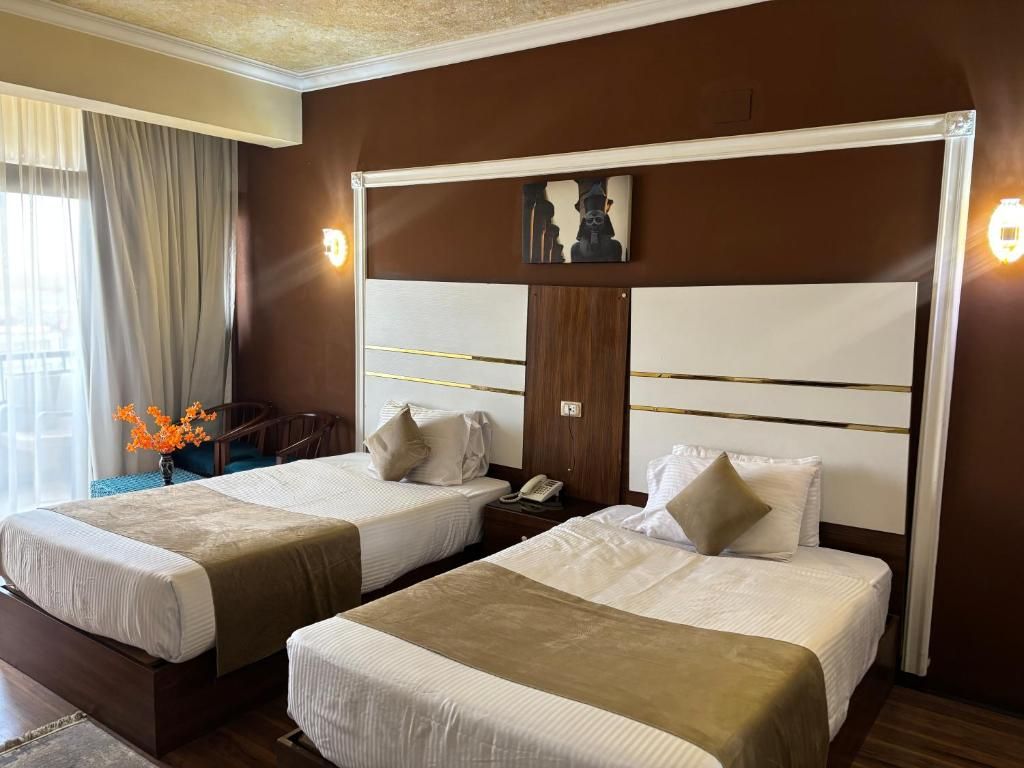 Habitación de hotel con dos camas, una mesita de noche, un teléfono y un cuadro en la pared.
