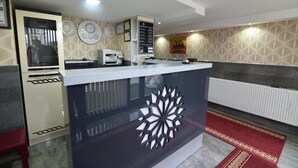 A reception desk with a modern design, a clock, and a framed certificate on the wall. - Saltuk Otel (Erzurum)