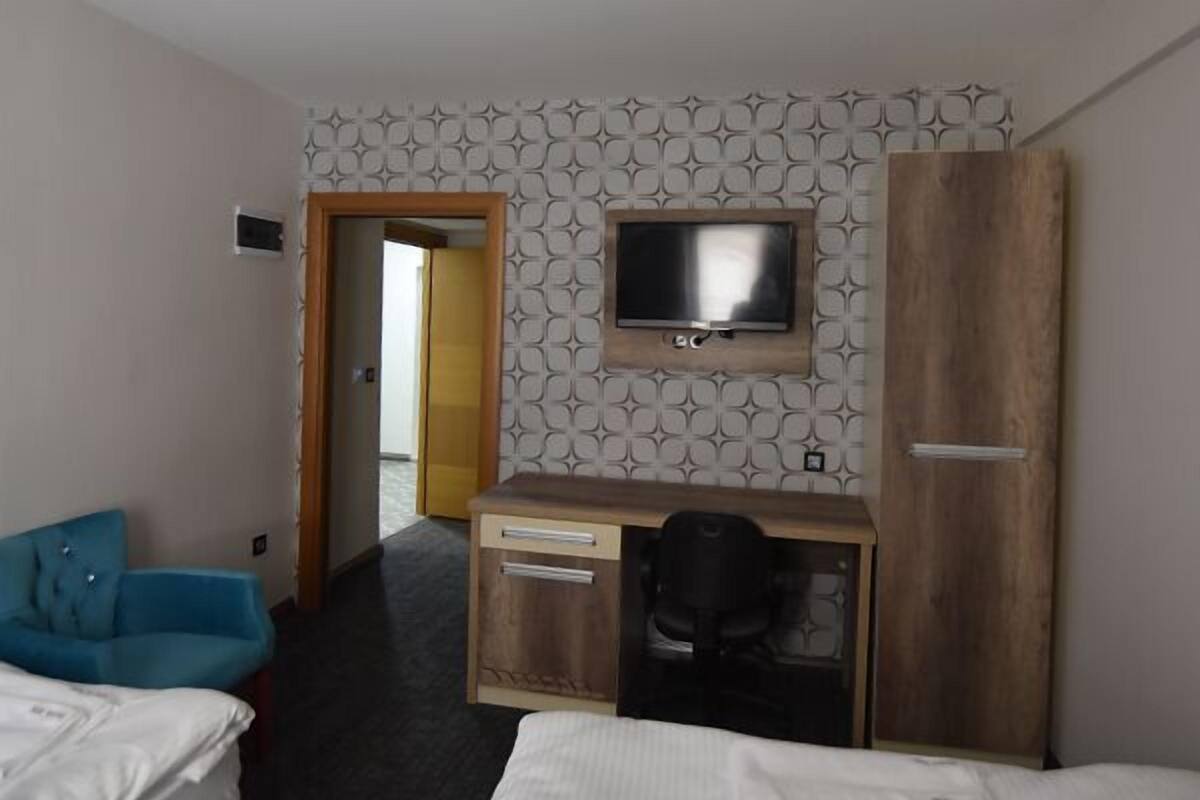 A hotel room with a bed, a desk with a chair, a television, and a blue sofa.