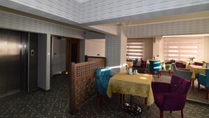 A restaurant with a modern interior, featuring a patterned ceiling, a wooden partition, and a variety of seating arrangements including tables and chairs. - Saltuk Otel (Erzurum)