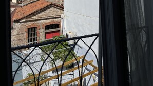 A view from a window overlooking a building with a red door and a white wall. - Macide Hanim Konagi (Ayvalik)