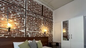 A hotel room with a brick-patterned wall, a wooden headboard, and a white wardrobe. - Macide Hanim Konagi (Ayvalik)