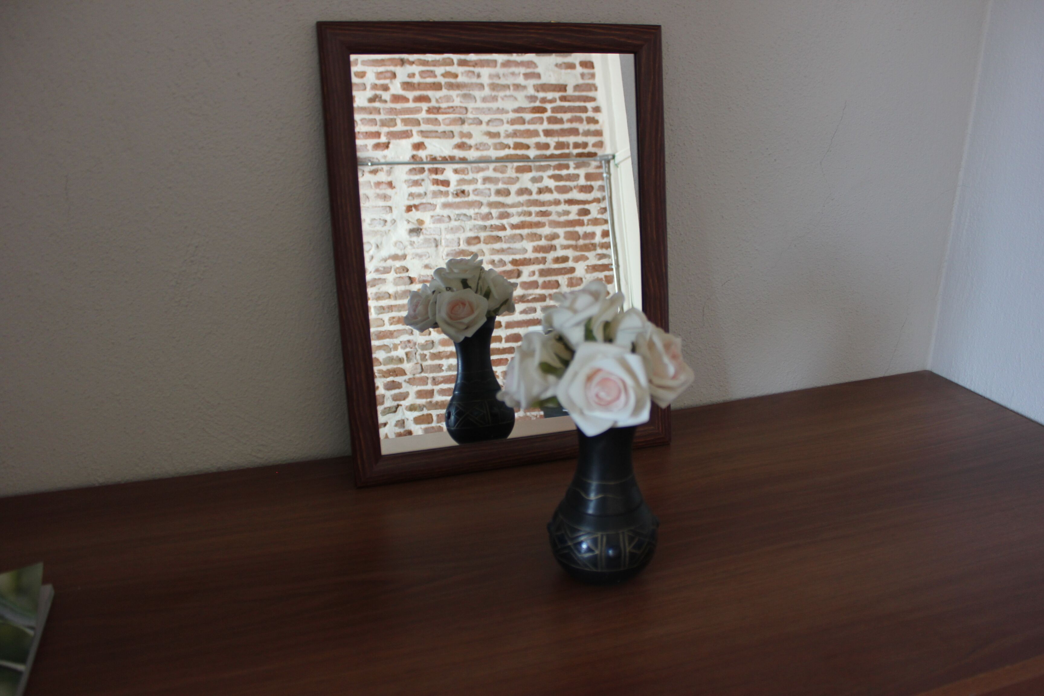 A wooden table with a vase of white flowers.