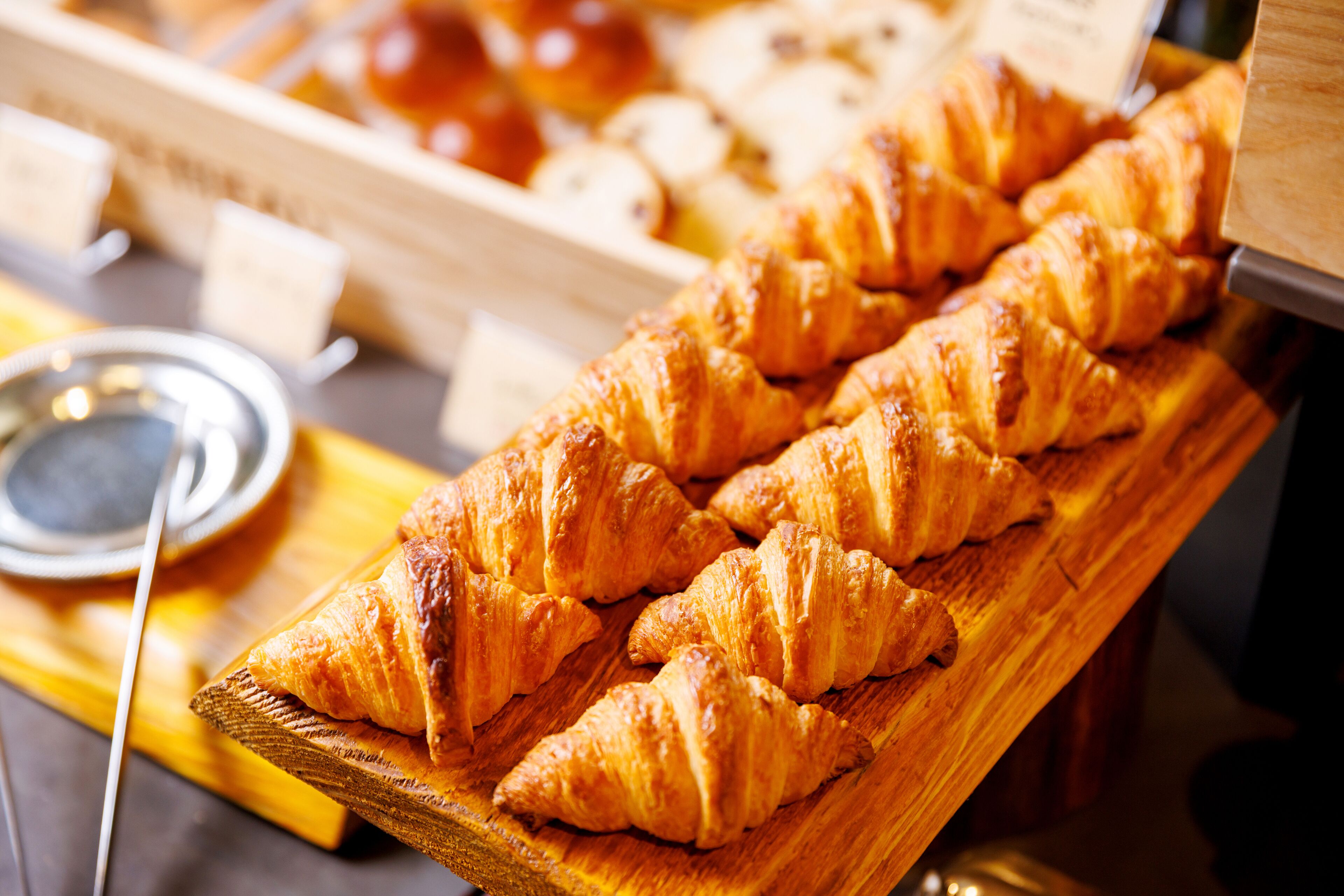 A wooden board with several golden-brown croissants.