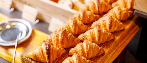 Una tabla de madera con varios croissants dorados y tostados.