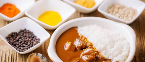 A bowl of curry with rice and various spices in small bowls.