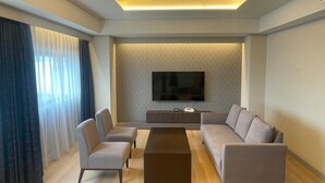 A modern living room with a flat-screen TV, two sofas, a coffee table, and a patterned wall. - Sendai Kokusai Hotel (Sendai)
