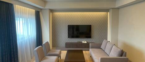 Un salon moderne avec un téléviseur à écran plat, deux canapés, une table basse et un mur orné d’un motif.