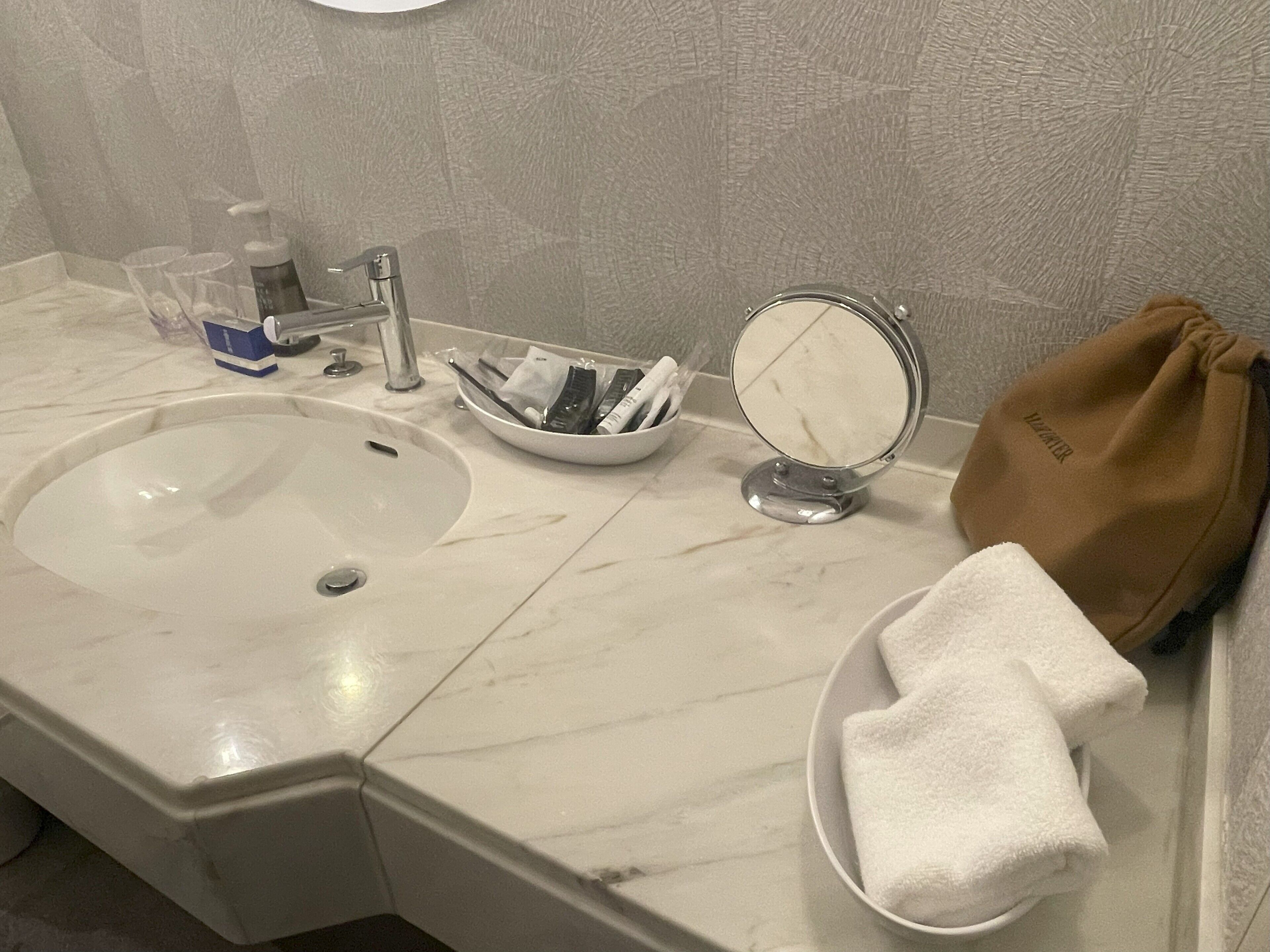 Un baño con lavamanos, espejo y toallero.