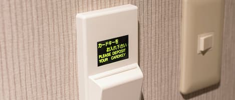 Un lector de tarjetas con un mensaje en japonés, un interruptor de luz y una pared con textura.
