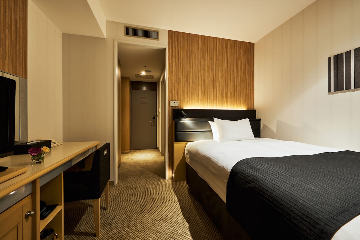 Une chambre d’hôtel avec un lit, un bureau et une chaise.