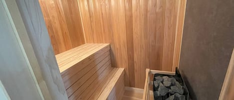 Un sauna avec des murs en bois, un banc et un appareil de chauffage.