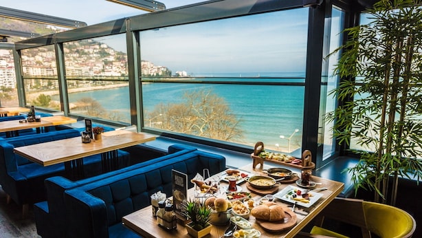 Un restaurant offrant une vue sur la mer, avec des sièges bleus et une variété de plats disposés sur les tables.