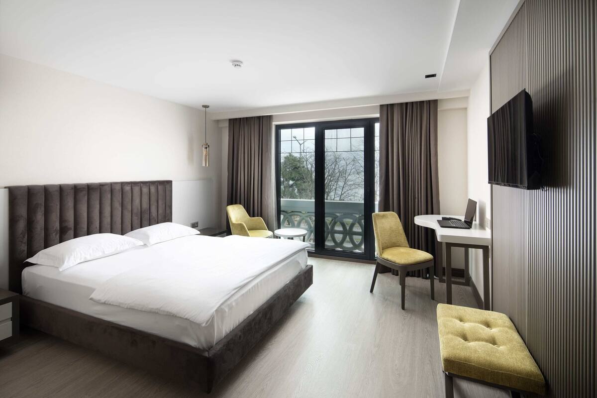 Una habitación de hotel moderna con una cama grande, un escritorio, una silla y un televisor.