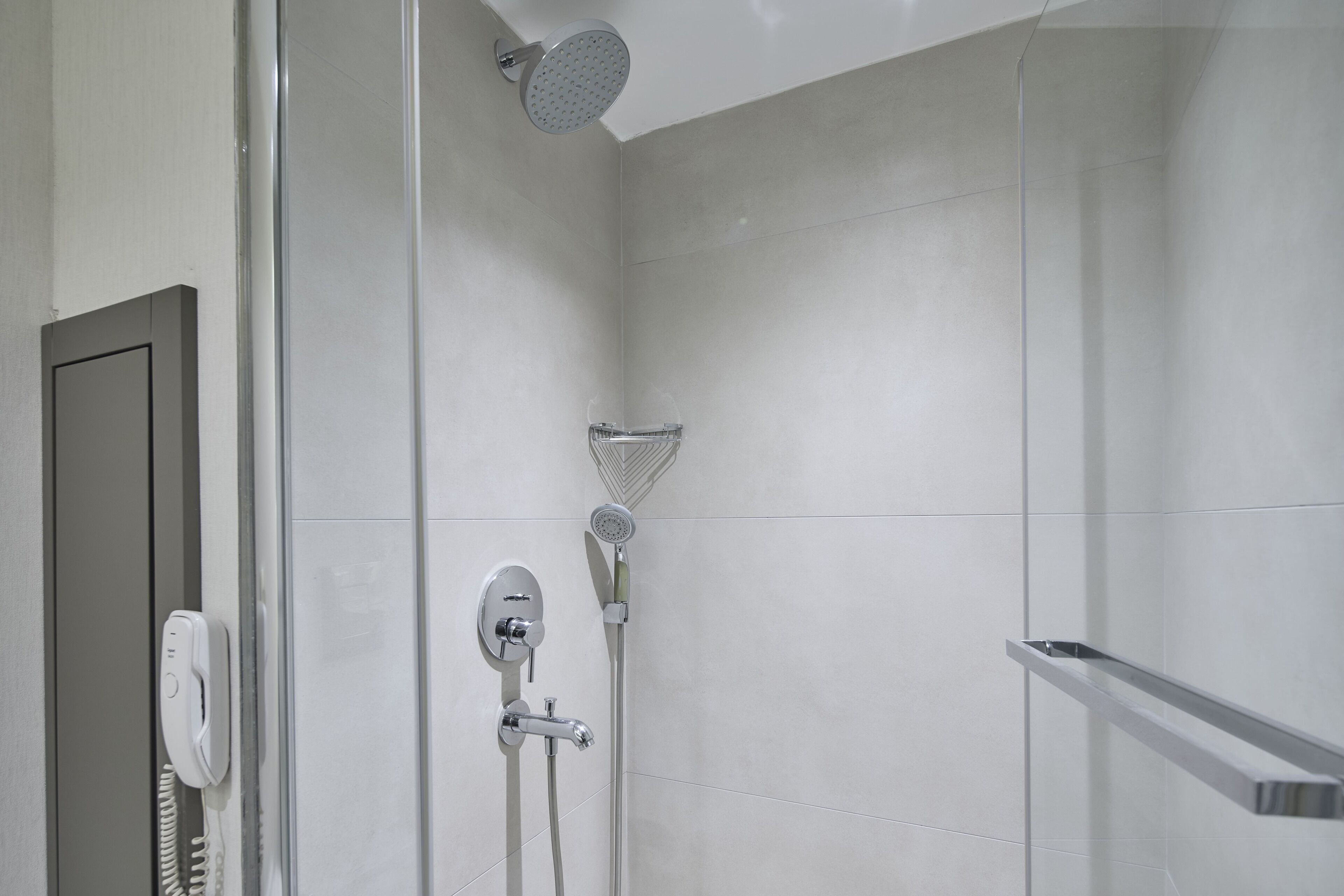 A modern shower with a handheld showerhead and a wall-mounted rain showerhead.