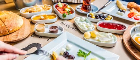 Variedad de alimentos en una mesa, incluyendo pan, aceitunas y salsas.