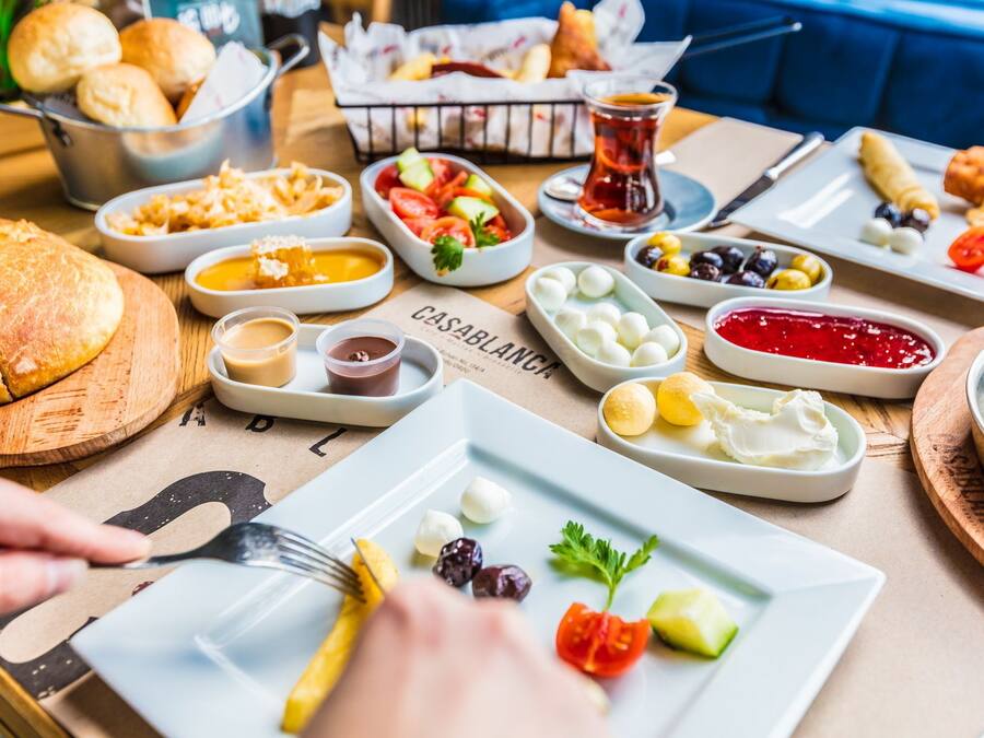 Diverse soorten eten op een tafel, zoals brood, olijven en dipsauzen.