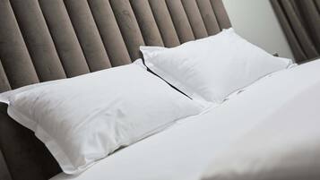 A bed with white bedding and a grey upholstered headboard.