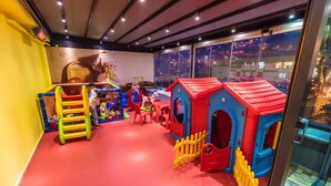 Un espace de jeux pour enfants avec des structures colorées, une piscine à balles et une échelle.