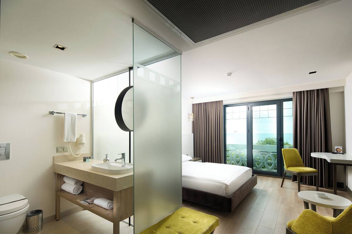 Una habitación de hotel con baño, cama, escritorio y vistas al exterior.