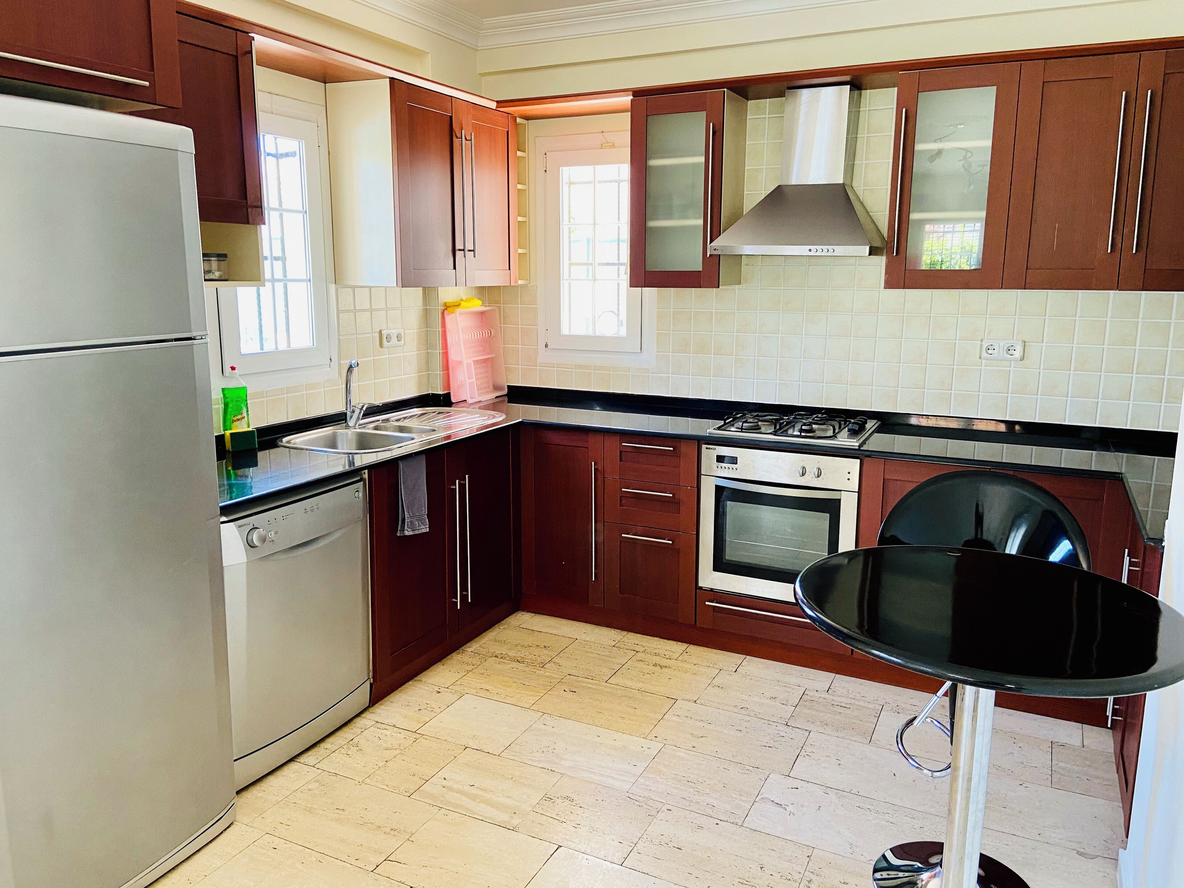 A modern kitchen with wooden cabinets, a stainless steel refrigerator, a gas stove, and a dishwasher.