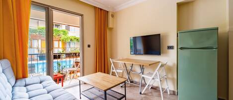 A compact living space with a sofa, a small table, a TV, and a refrigerator.