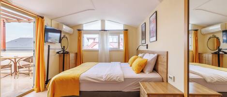 Une chambre d’hôtel comprenant un lit, une table de chevet, une télévision et un balcon avec une table et des chaises.