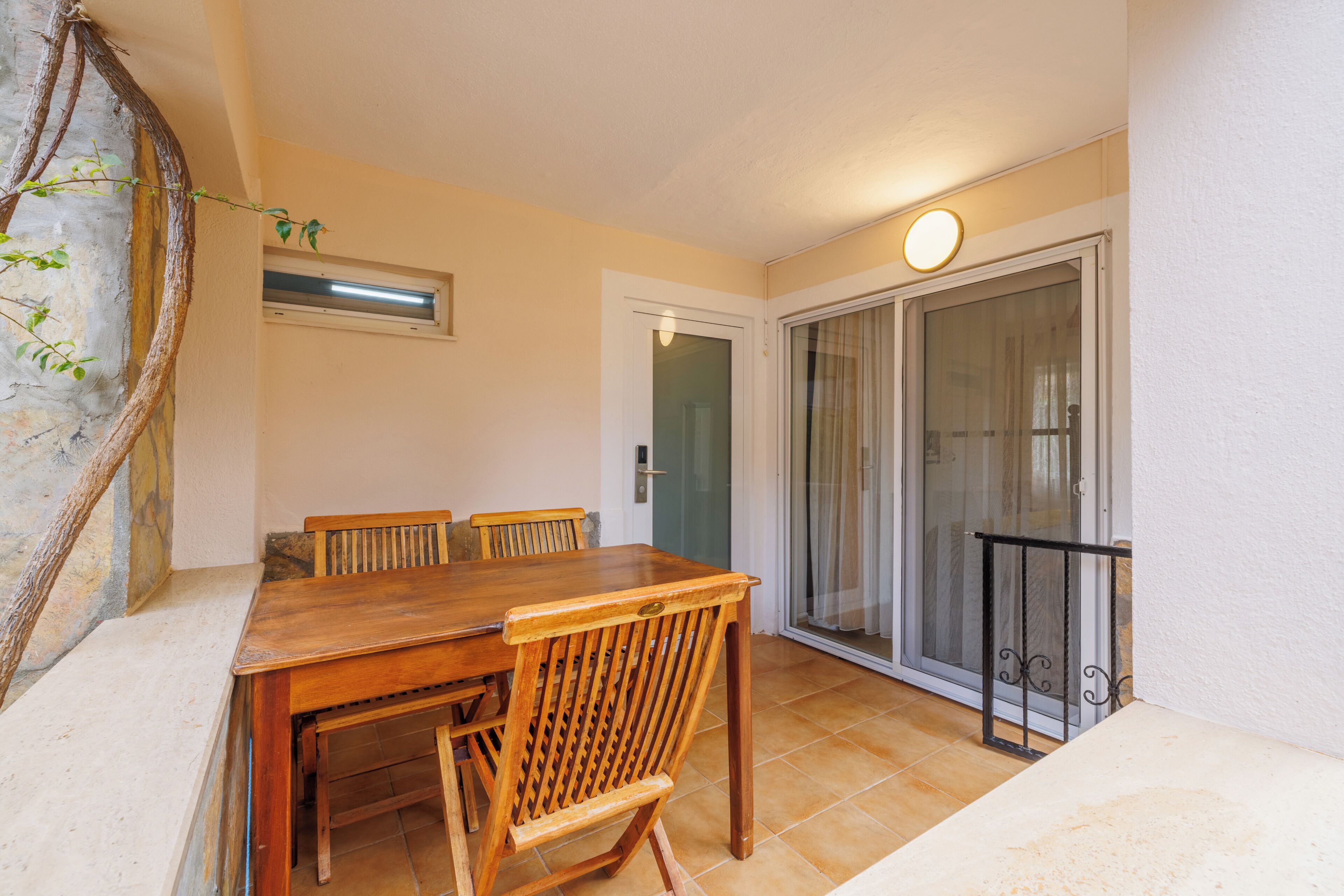 Un comedor con una mesa y sillas de madera, un puerta corrediza de vidrio y un ventanal pequeño.